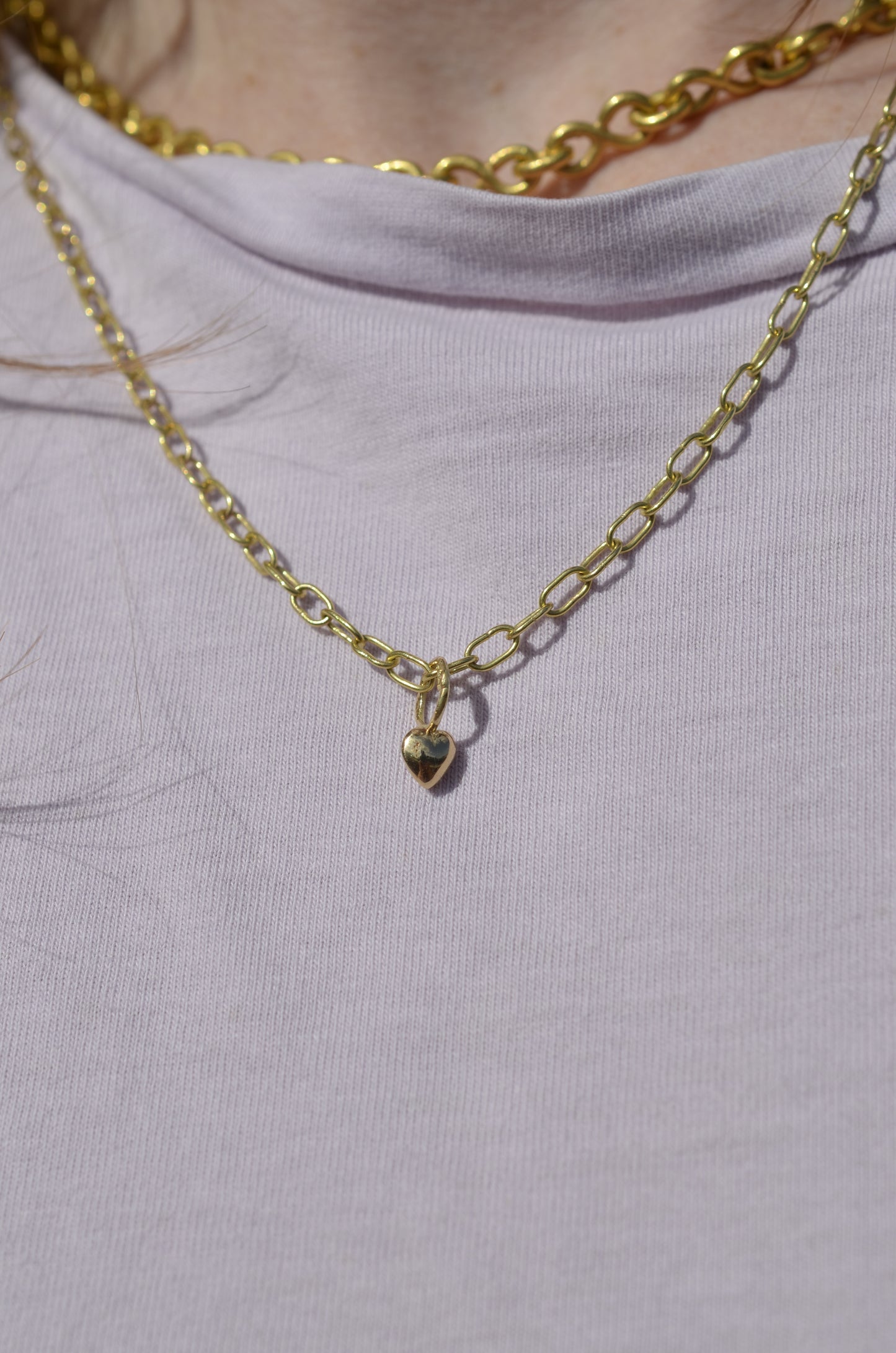 heart shaped pendant in 18 karat gold on gold chain worn