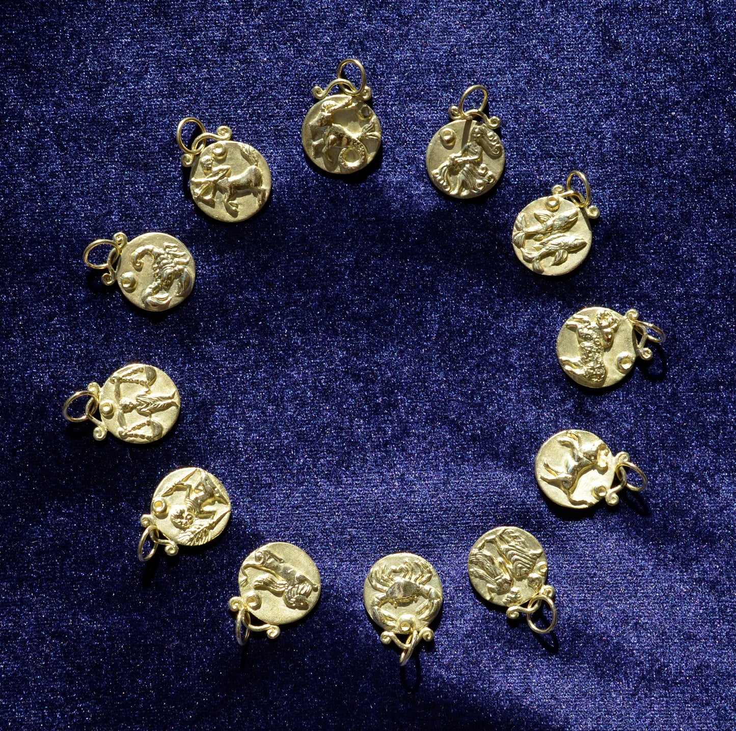 12 zodiac pendants in 18 karat gold on blue velvet
