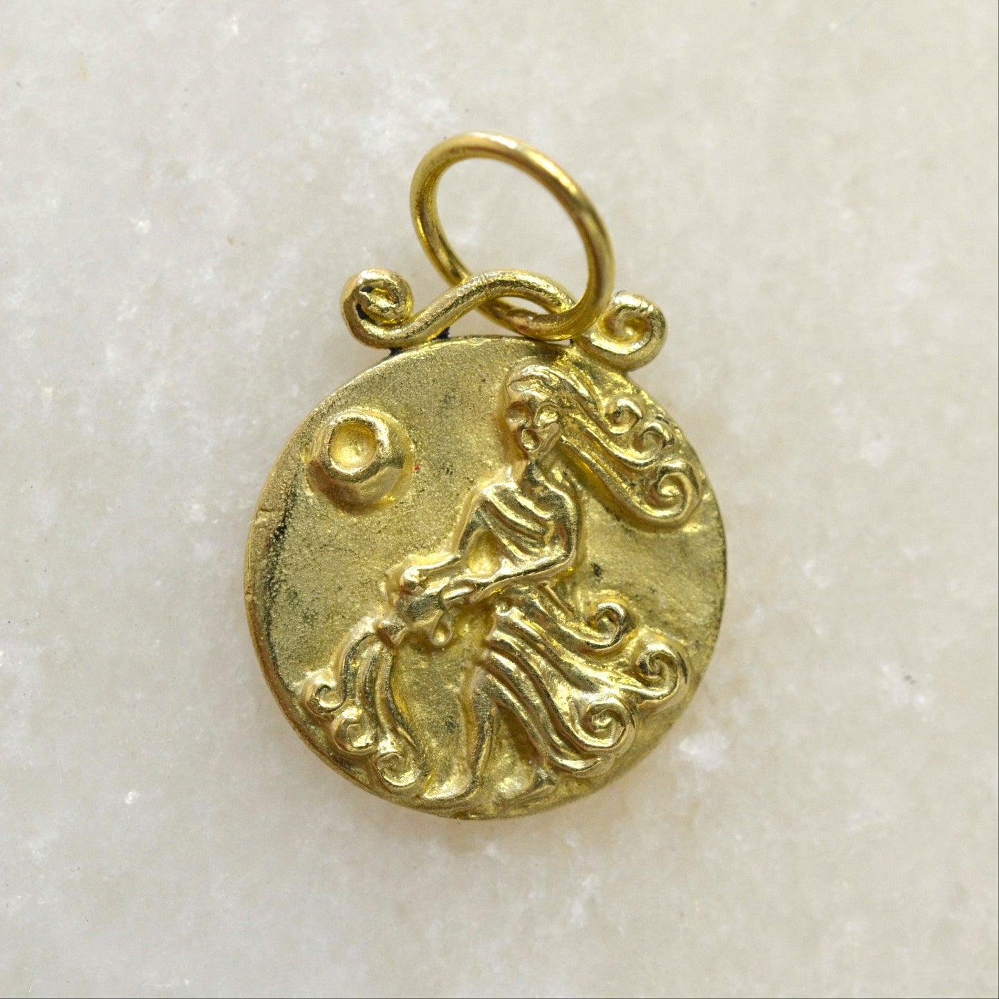Aquarius zodiac pendant in 18 karat gold on marble