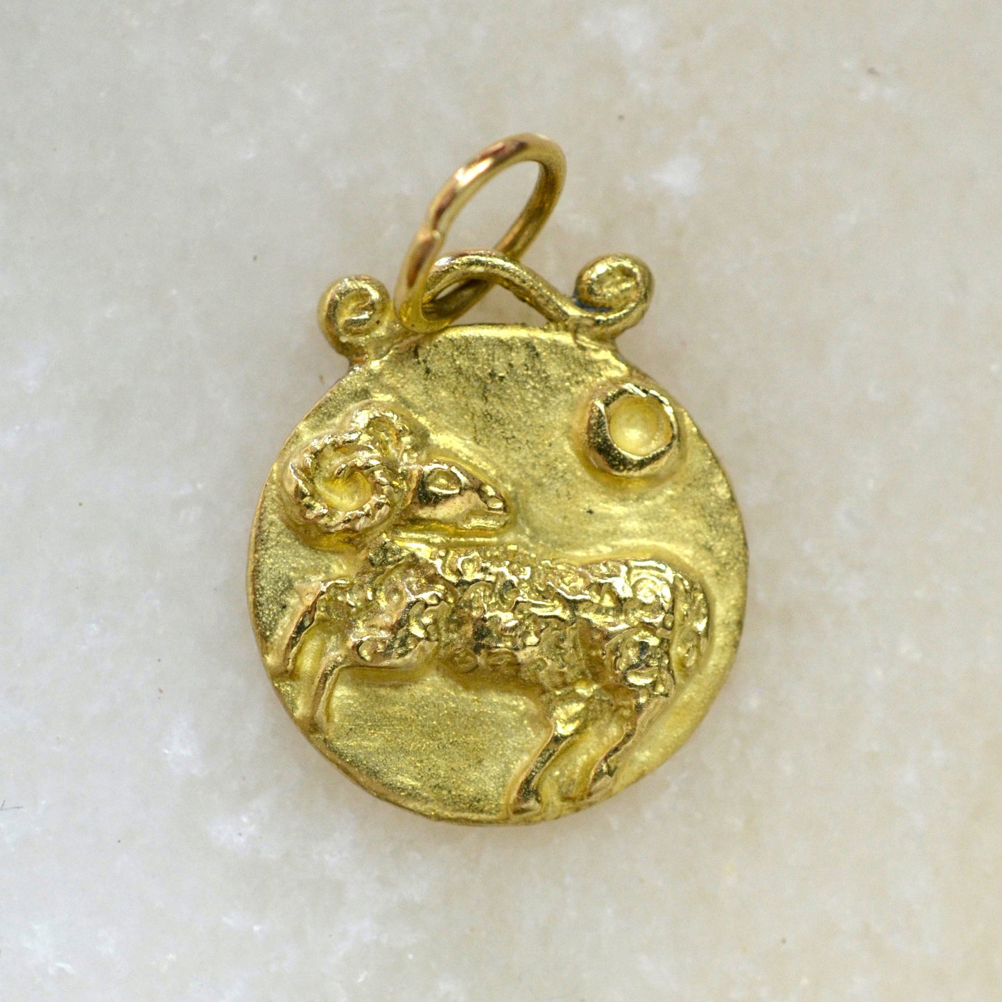 Aries zodiac pendant in 18 karat gold on marble