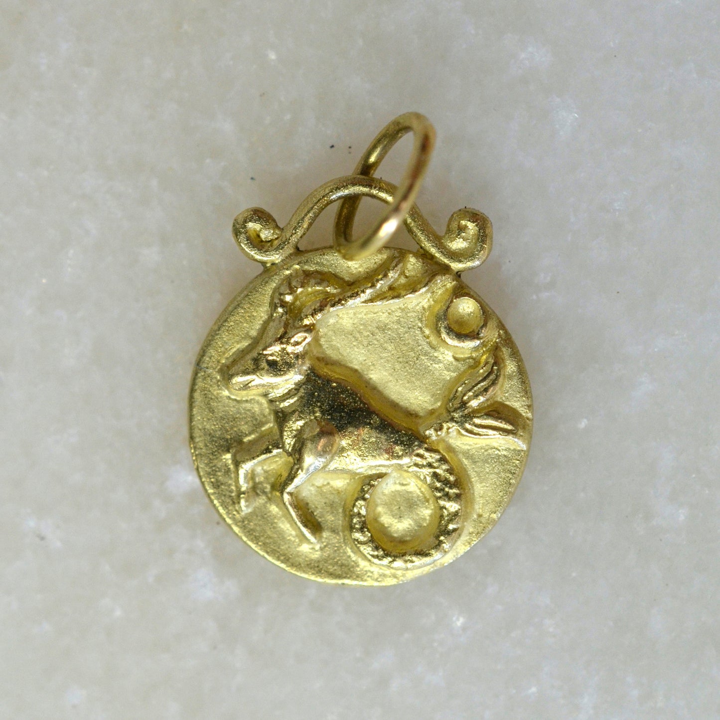 Capricorn zodiac pendant in 18 karat gold on marble