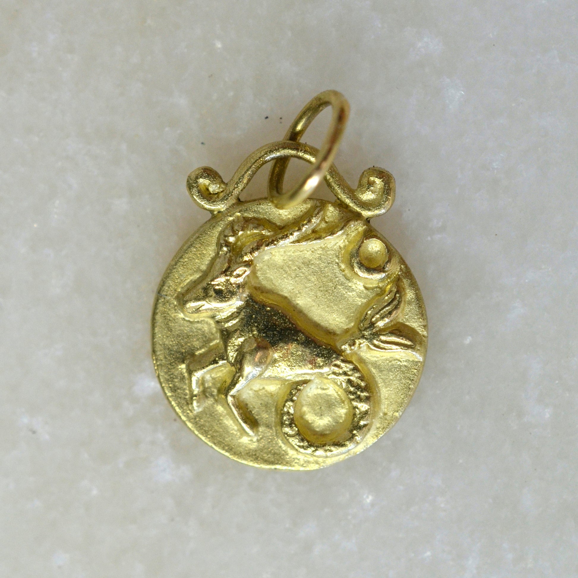 Capricorn zodiac pendant in 18 karat gold on marble