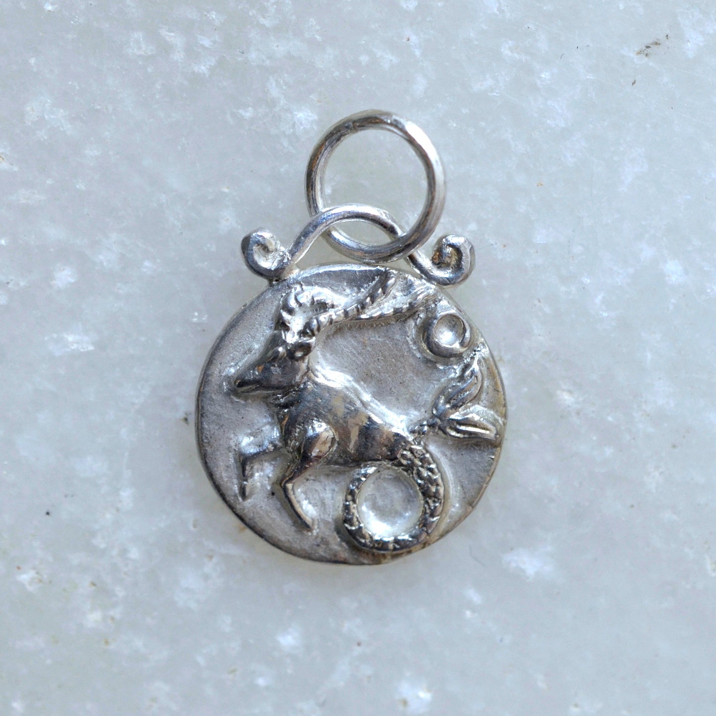 Capricorn zodiac pendant in silver on marble
