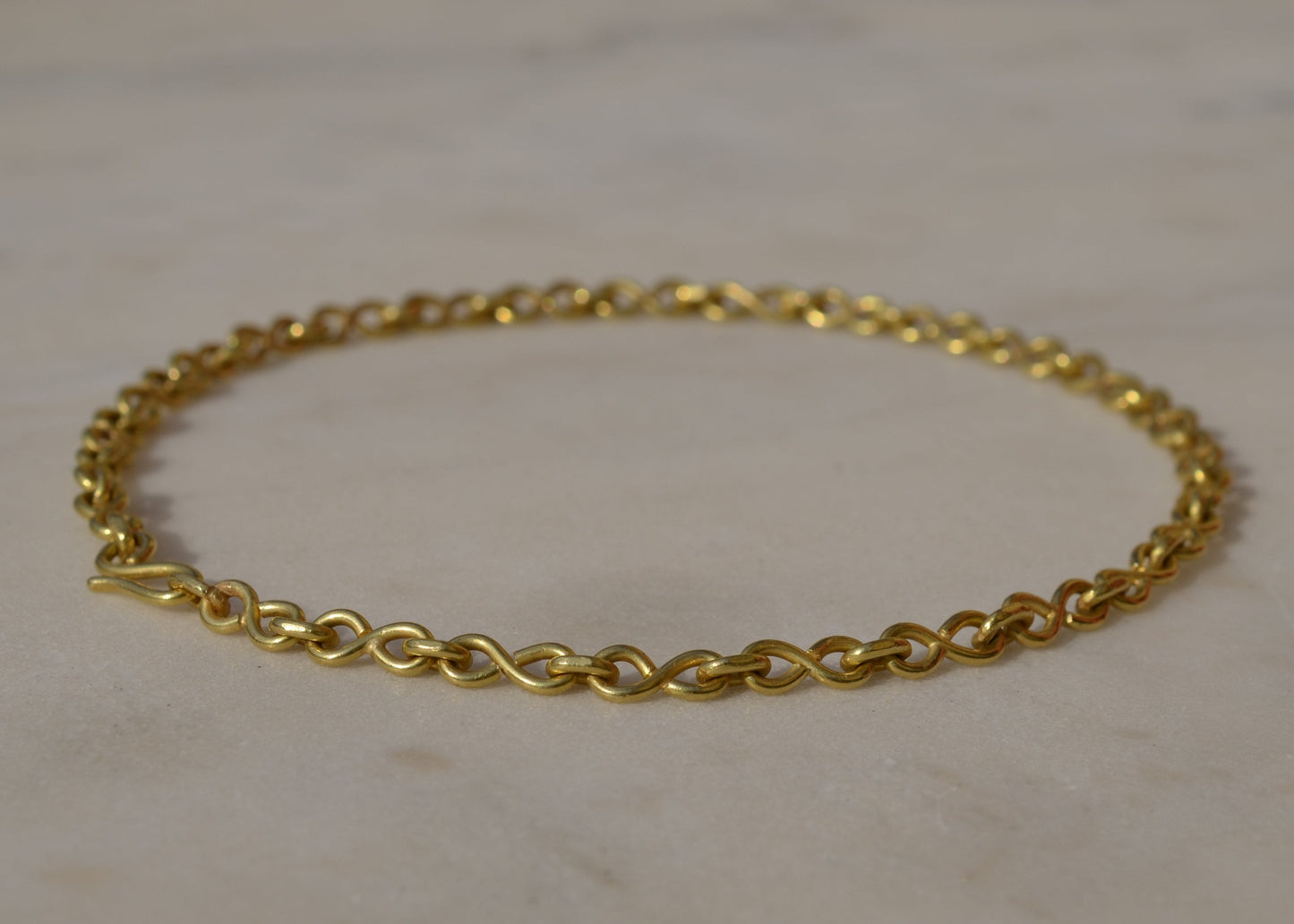Gold chain bracelet on a light marble background