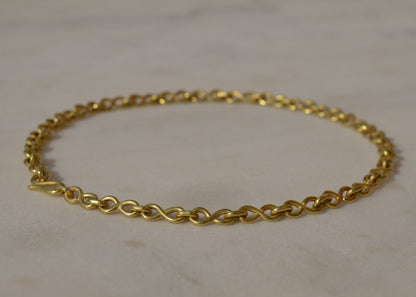 Gold chain bracelet on a light marble background