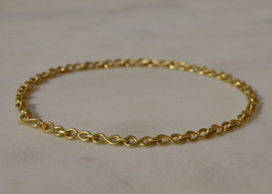Gold chain bracelet on a light marble background
