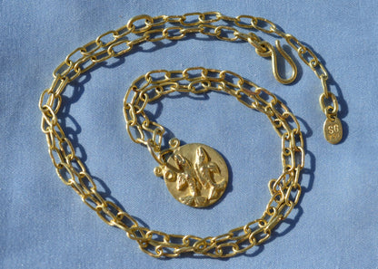 Pisces zodiac pendant on a handmade chain necklace on blue fabric