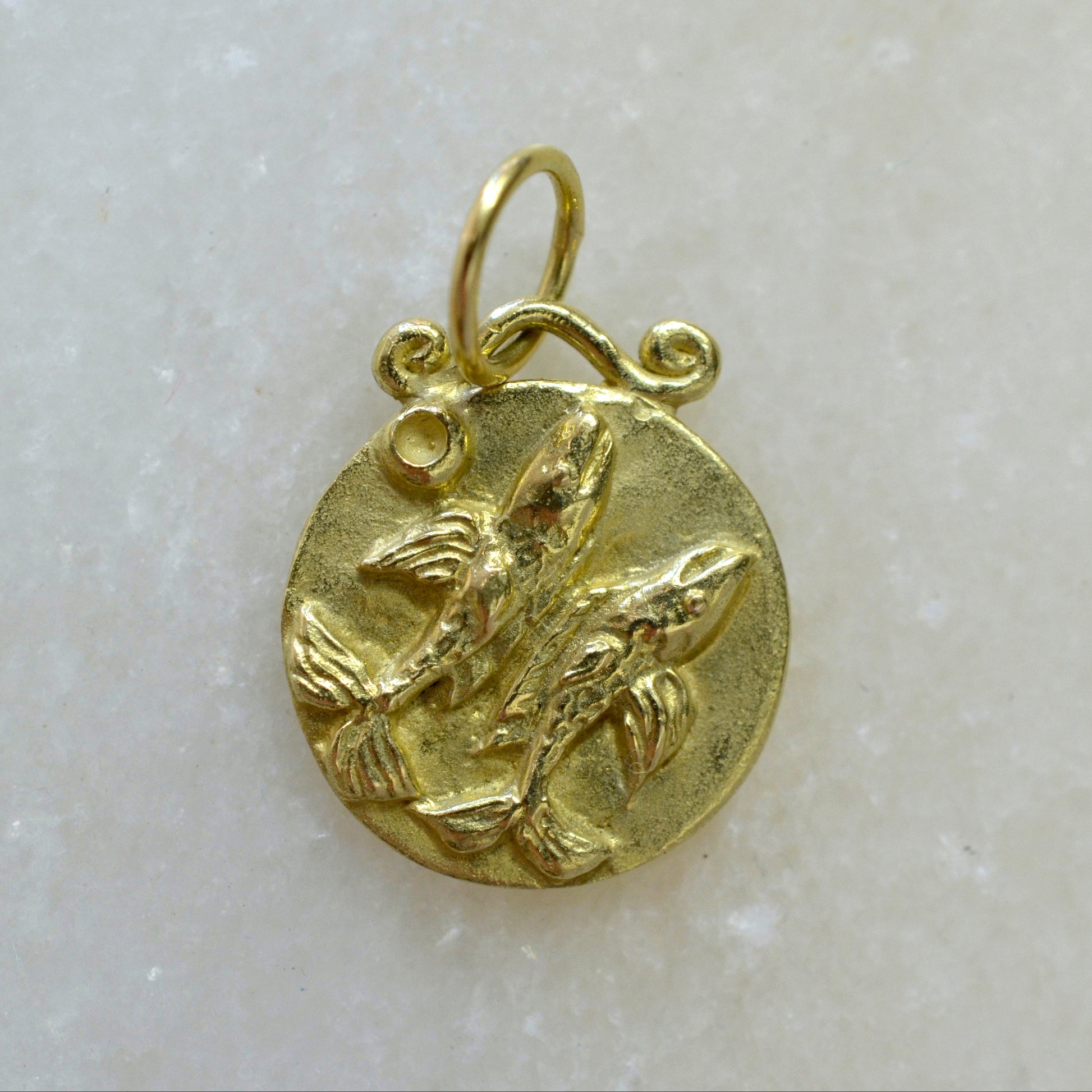 Pisces zodiac pendant in 18 karat gold on marble