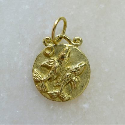 Pisces zodiac pendant in 18 karat gold on marble