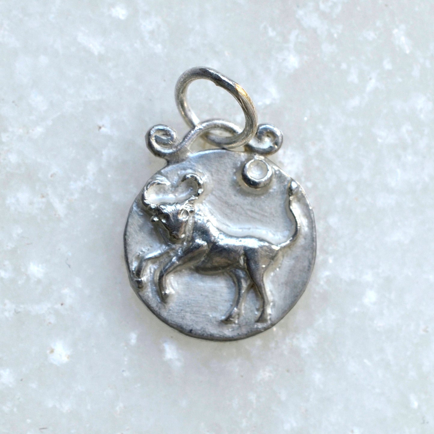 Taurus zodiac pendant in silver on marble