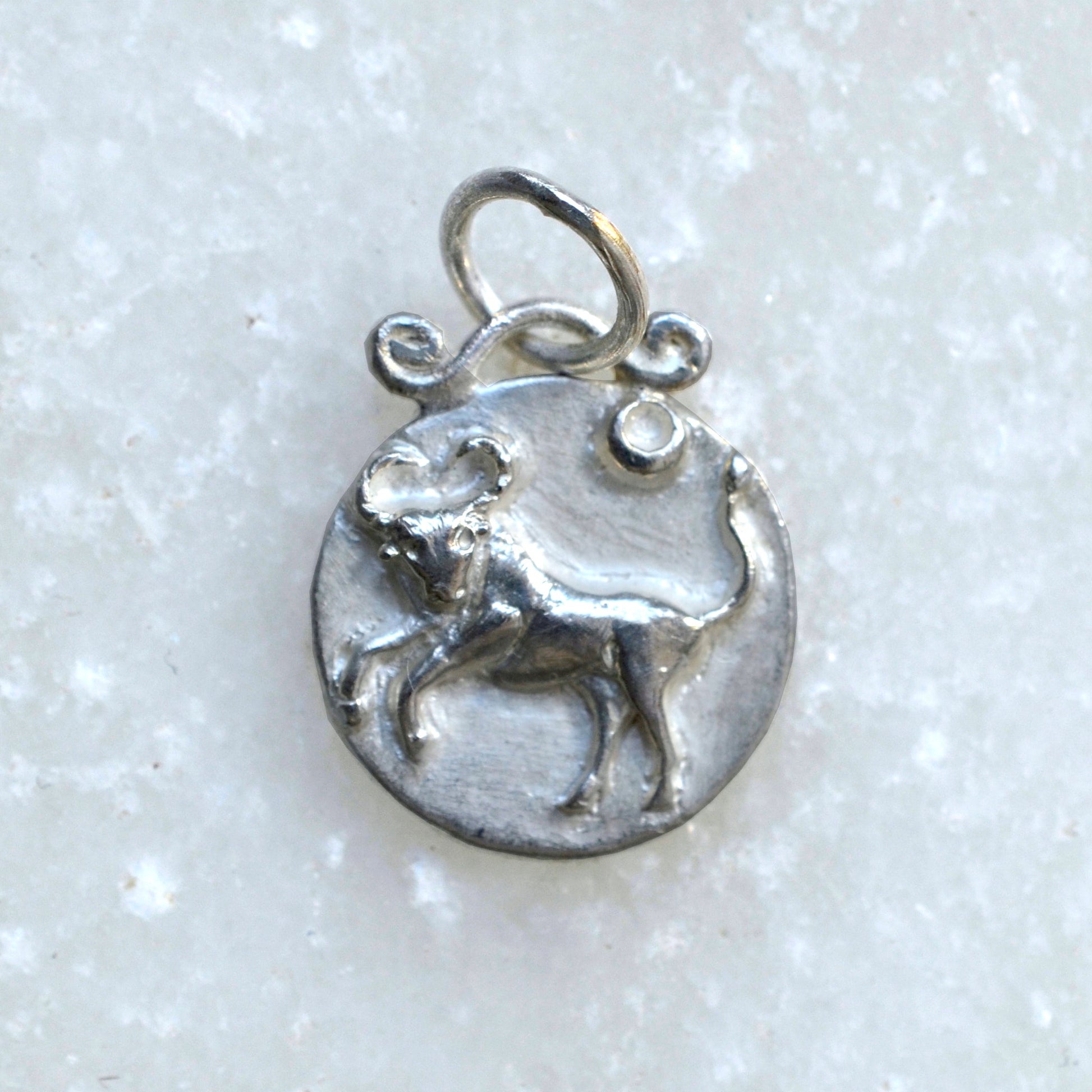 Taurus zodiac pendant in silver on marble