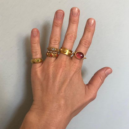 Hand with several gold rings with colourful gemstones
