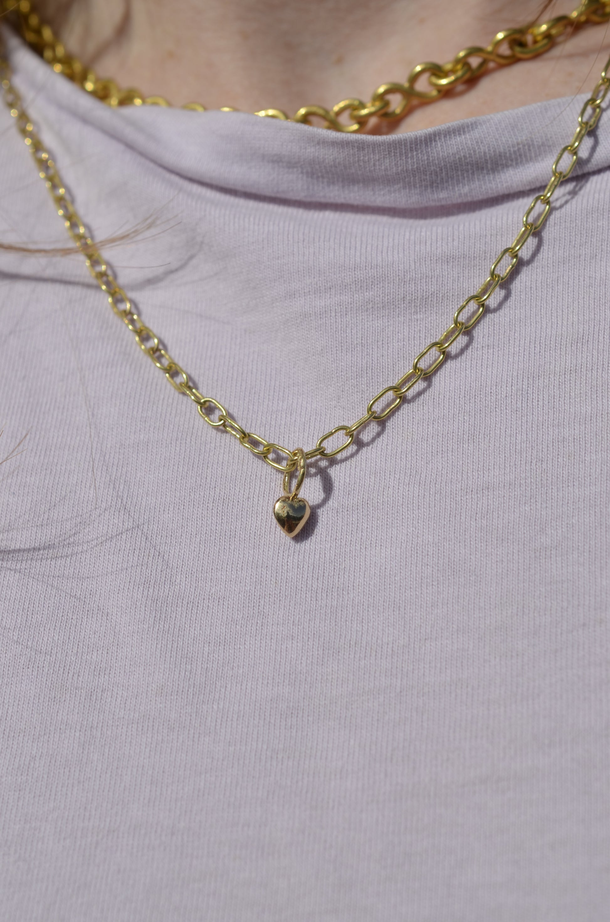 heart shaped pendant in 18 karat gold on gold chain worn