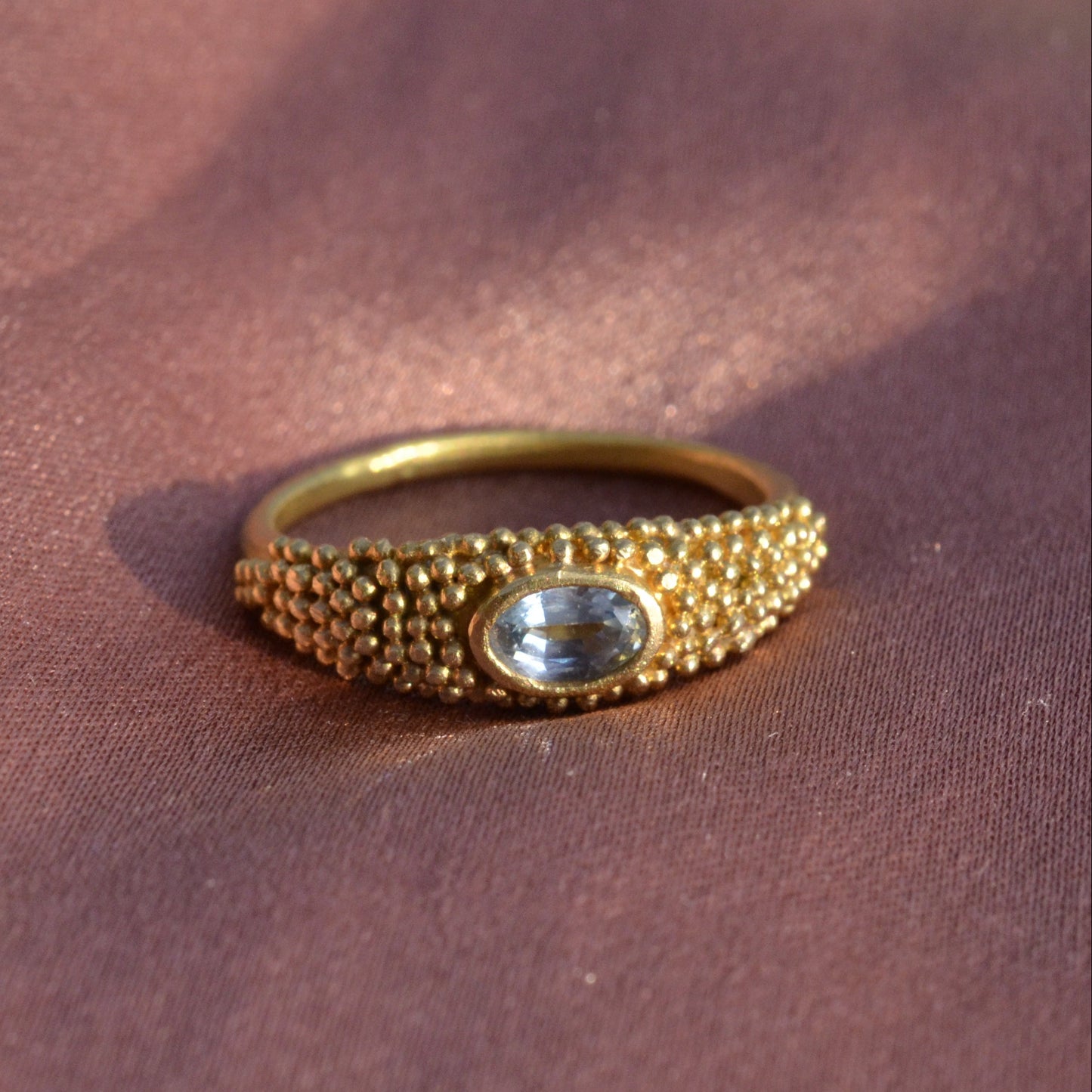 Granulated gold ring with a blue topaz on silk