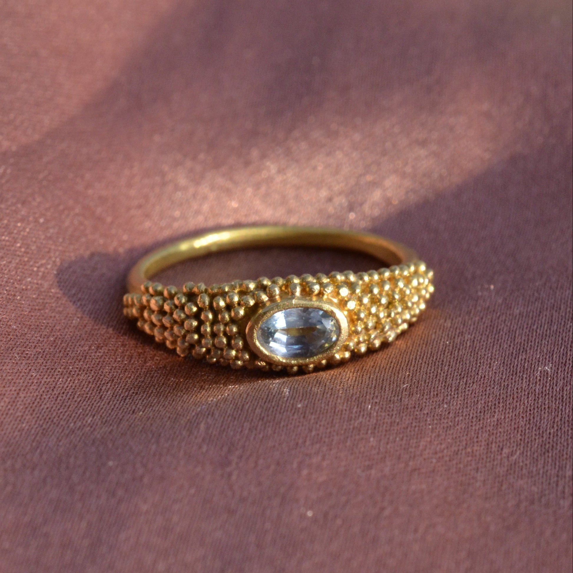 Granulated gold ring with a blue topaz on silk