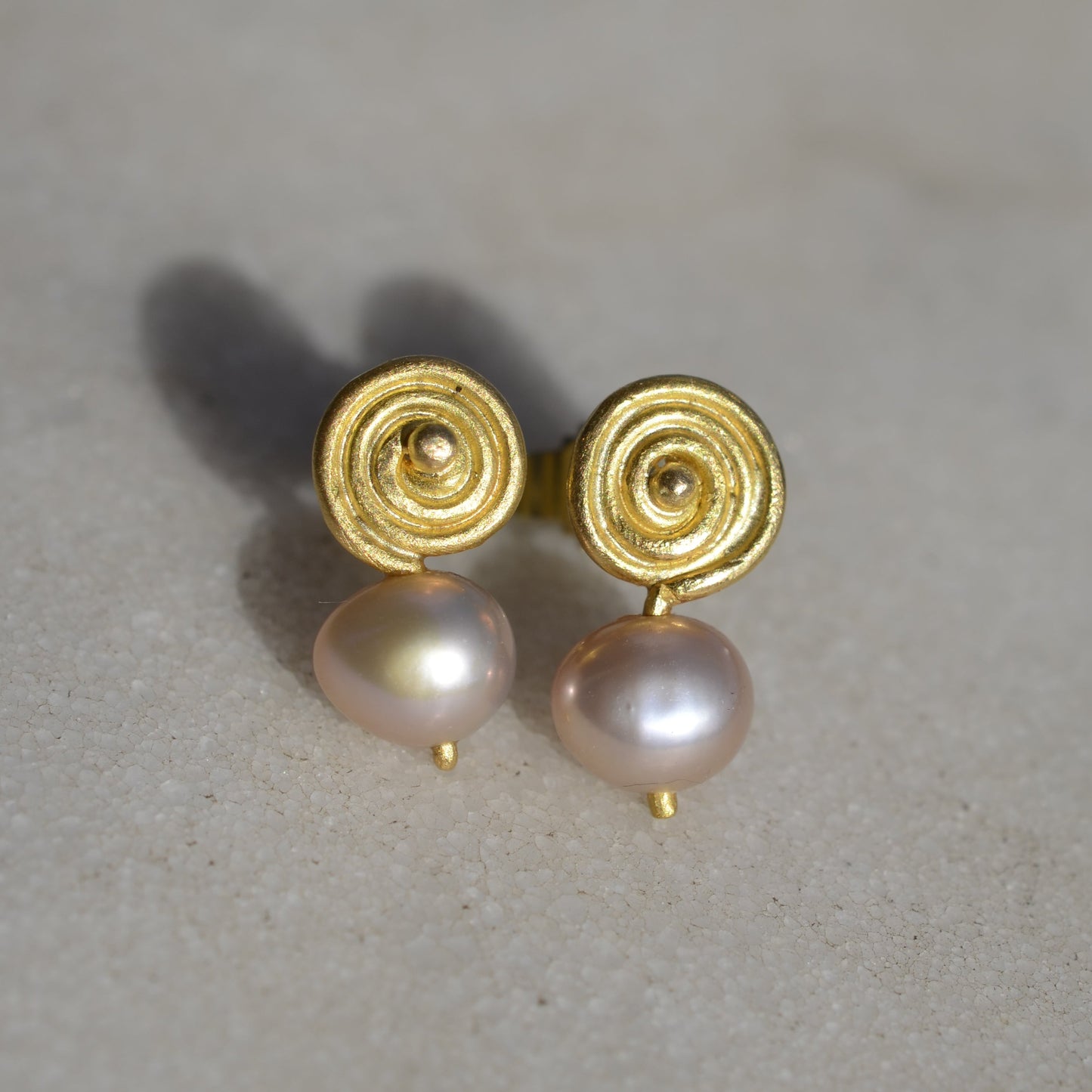 Gold earrings with pink pearls on marble