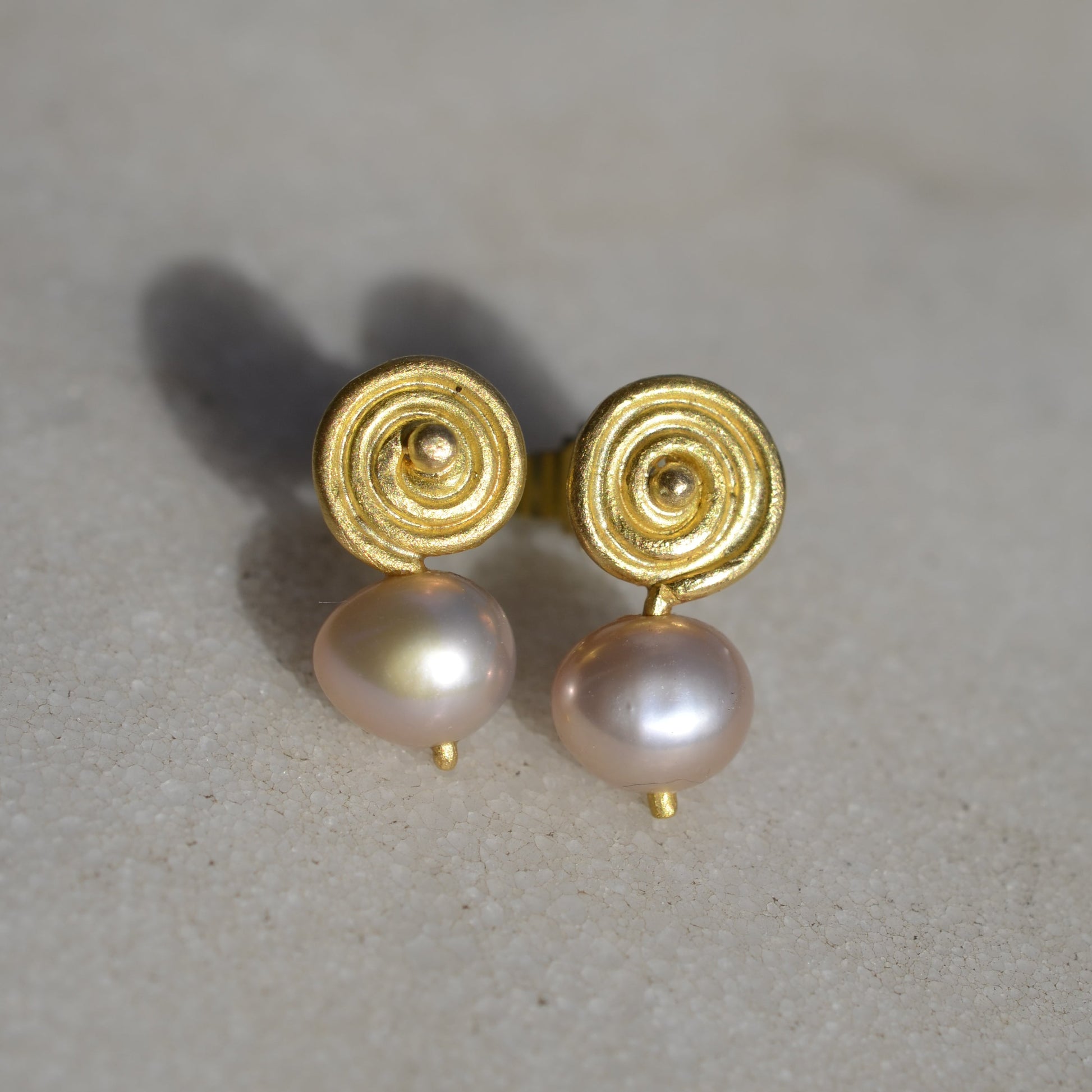 Gold earrings with pink pearls on marble