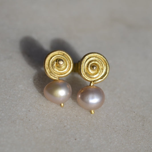 Gold earrings with pink pearls on marble
