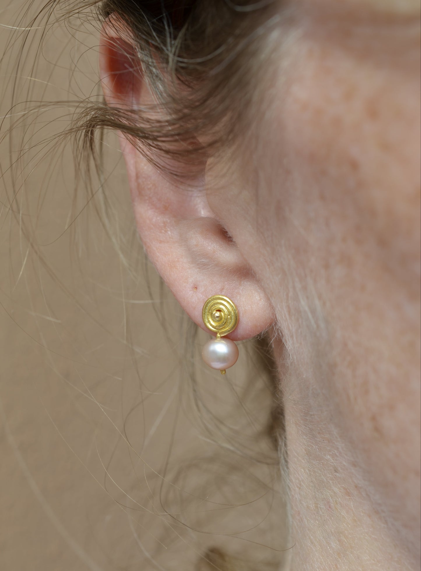 Gold earring with pink pearls worn in ear