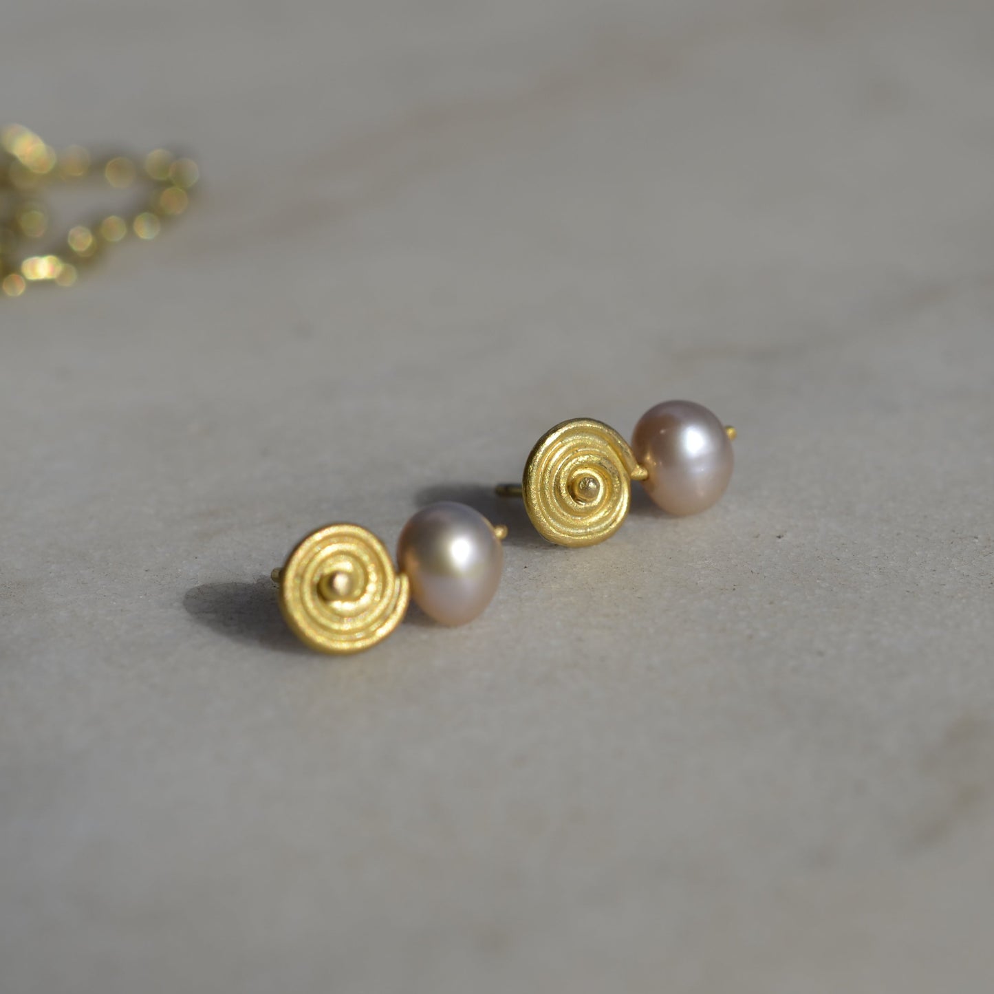 Gold and pink pearl earrings on marble 