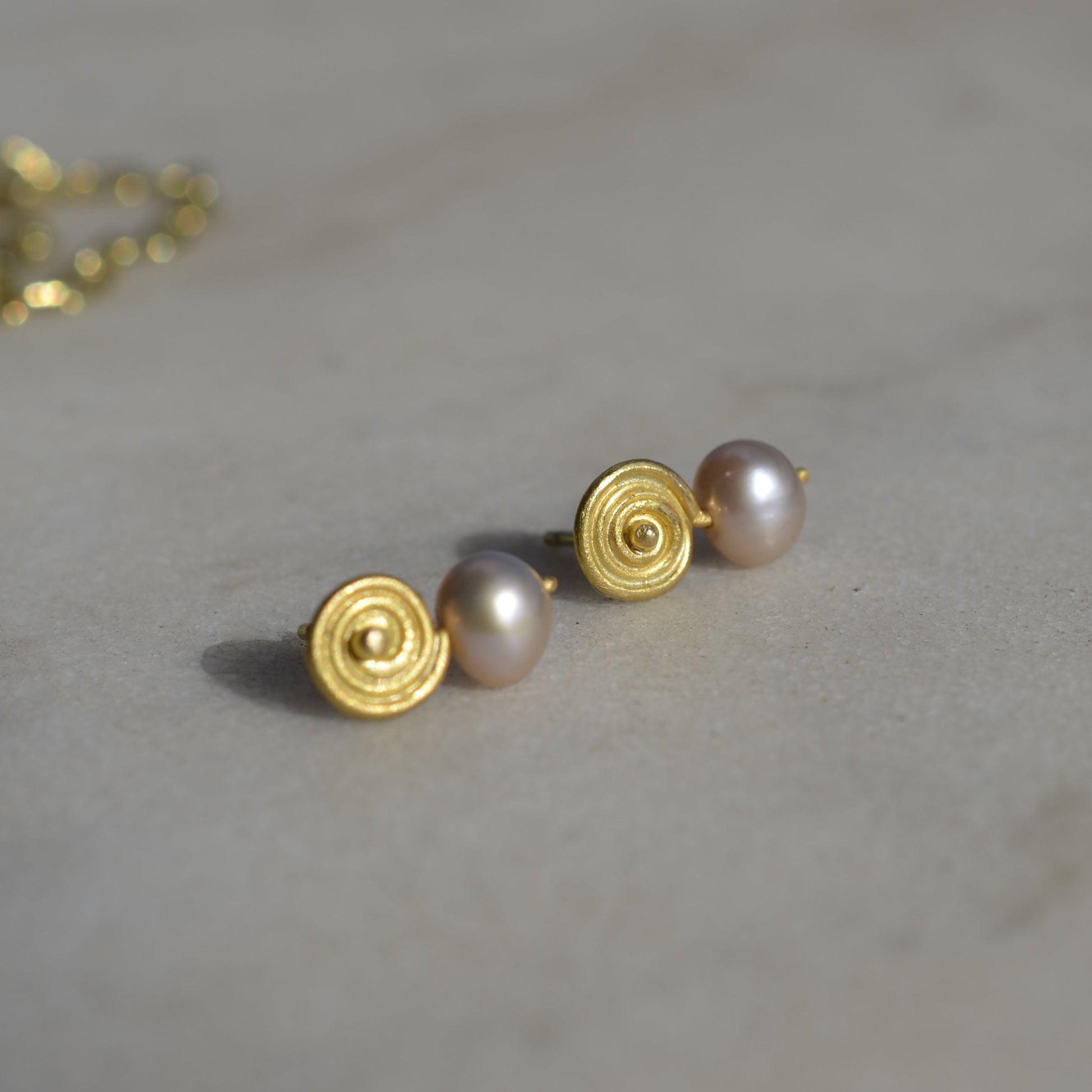 Gold and pink pearl earrings on marble 