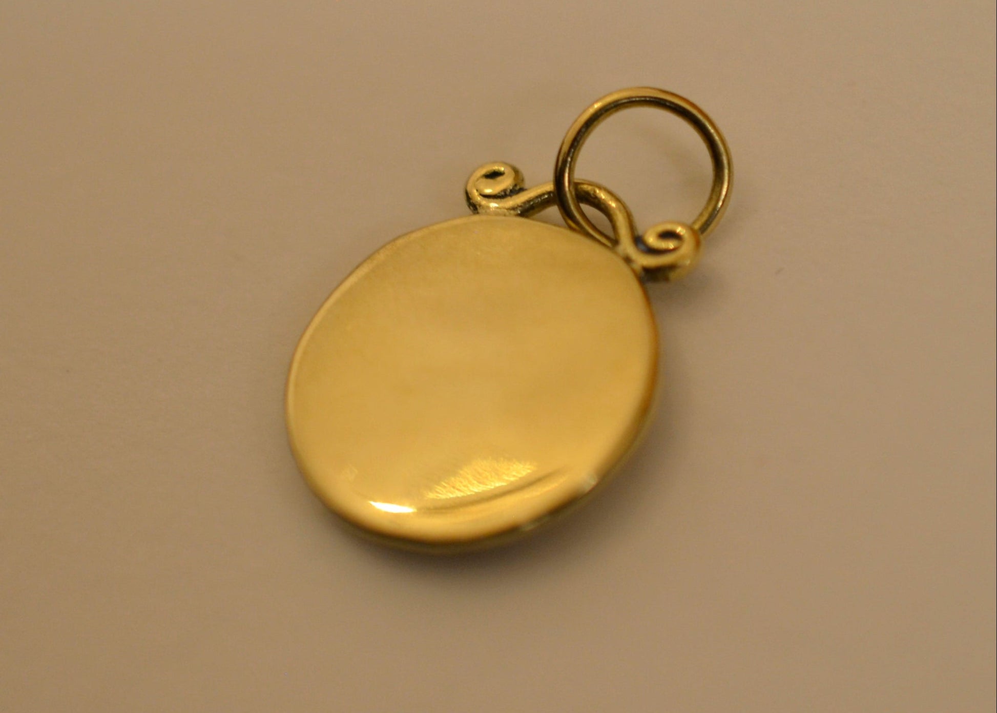 backside of zodiac pendants in 18 karat on dark white surface